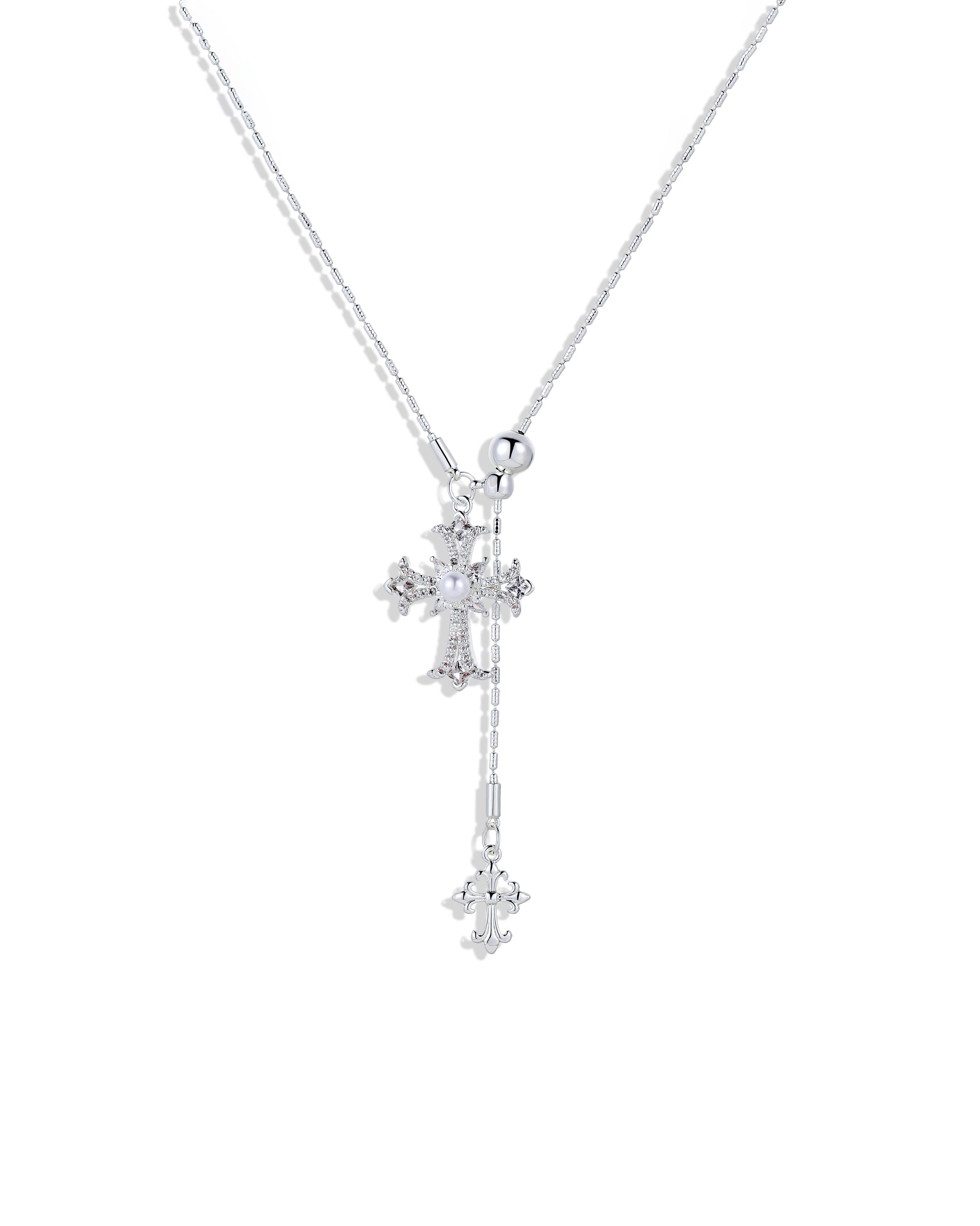 A model wearing a silver-plated cross pendant lariat necklace with an adjustable slider bead on a dark ribbed sweater.